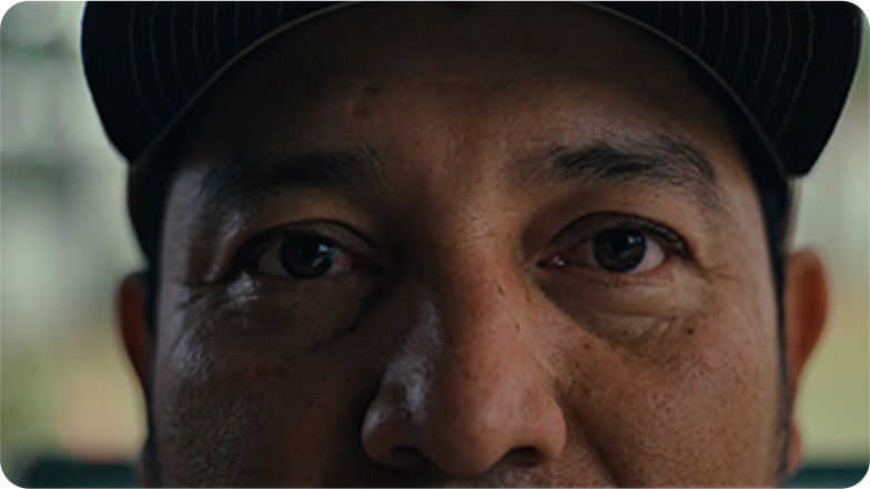 Primer plano del rostro de un hombre centrado en los ojos, con una gorra negra.